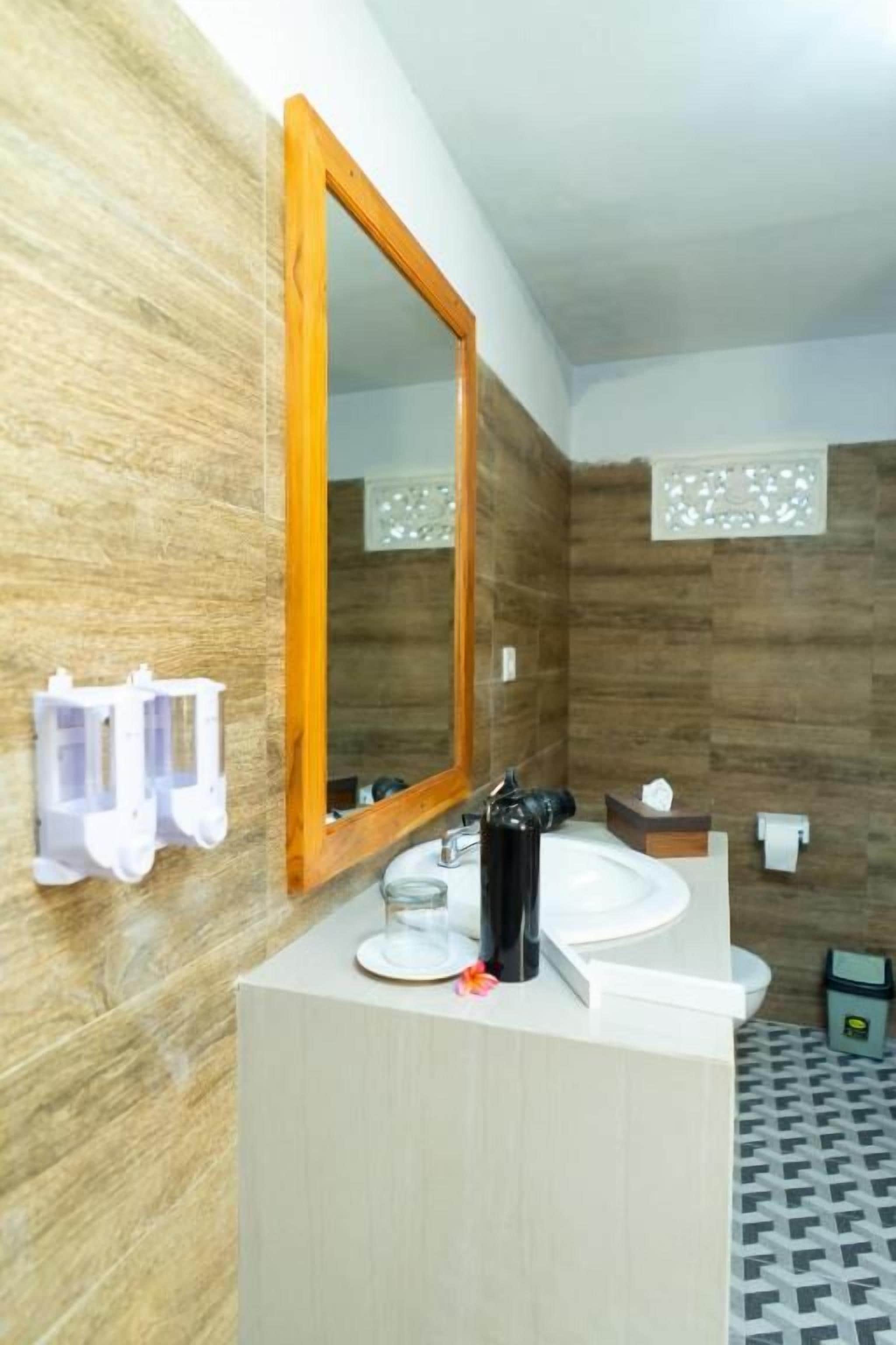 A bathroom with a wooden wall, a white sink, a mirror, and a patterned floor.