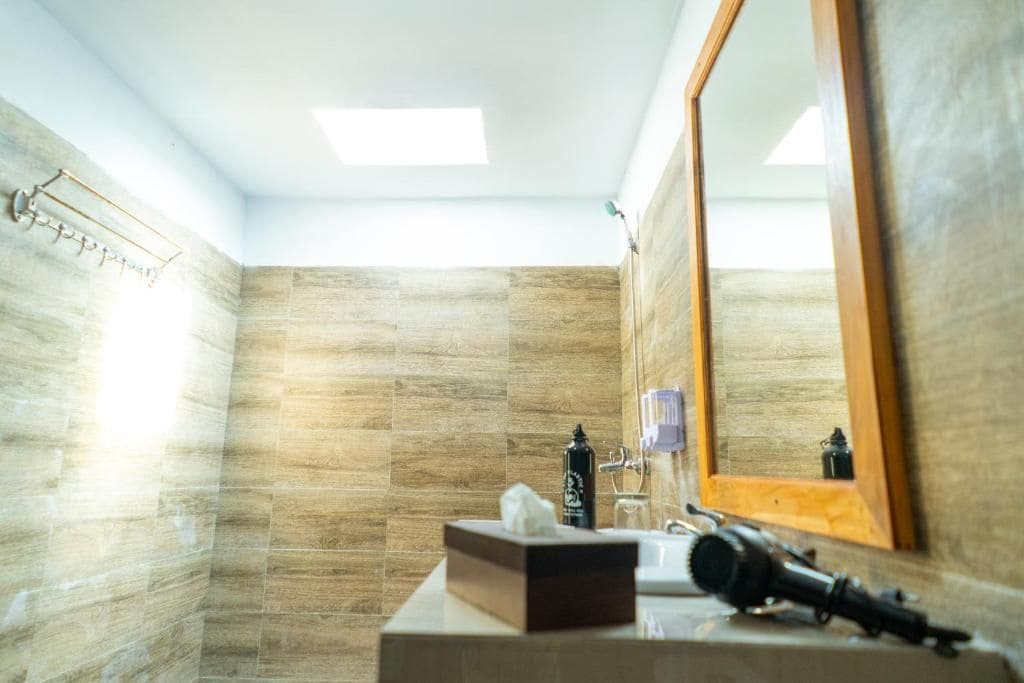 Ein Badezimmer mit Holzboden, einem Spiegel, einem Waschbecken, einem Handtuchspender und einer Taschentuchbox.