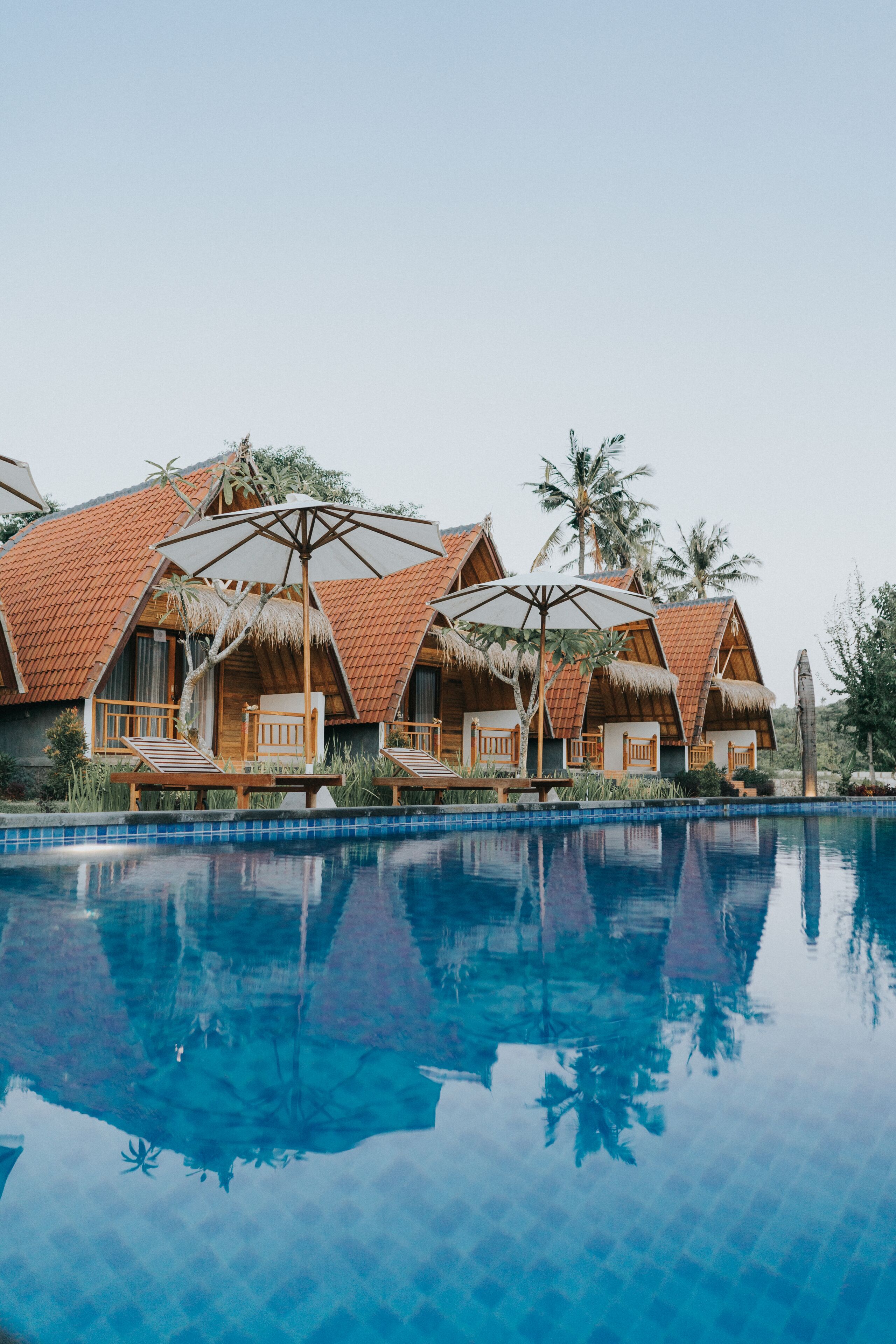 Un resort con cabañas de techo de paja, piscina y palmeras.