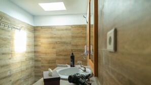 Un baño con pared de madera, un lavabo, un espejo y un secador de pelo en la encimera.