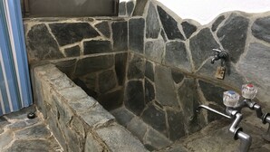 A stone bathtub with a metal faucet and a control knob. - Nasukogen Holiday (Nasu)
