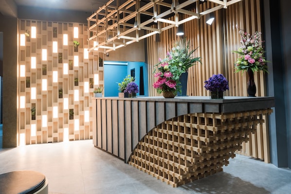 A reception desk with a modern design, featuring a wooden slat wall and a curved wooden structure beneath it.