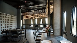 A modern dining area with a long table, multiple chairs, and a decorative centerpiece. - Little Loft Hotel (Wichit)