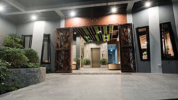 A modern lobby with a central elevator, potted plants, and a stone wall. - Little Loft Hotel (Wichit)