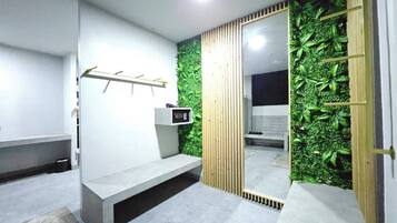 Un baño moderno con un banco gris, un estante en la pared y un jardín vertical verde.