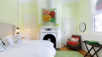Un dormitorio con cama, chimenea, sillón y ventana.