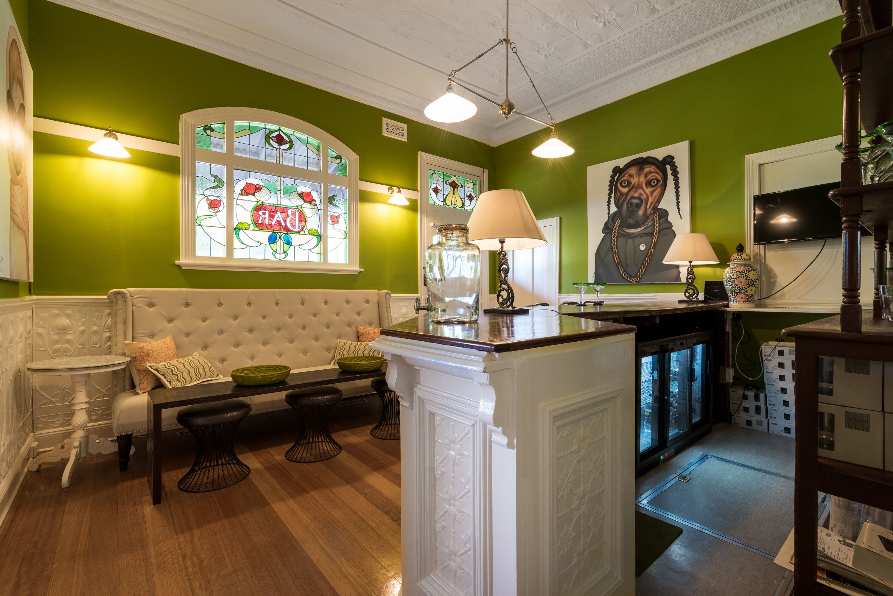 A green-walled room with a white sofa, a glass-top table, and a decorative lamp.
