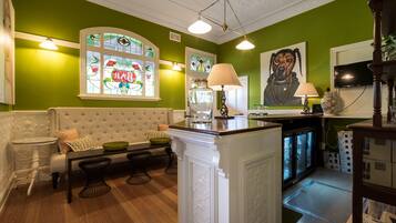 A green-walled room with a white sofa, a glass-top table, and a decorative lamp.