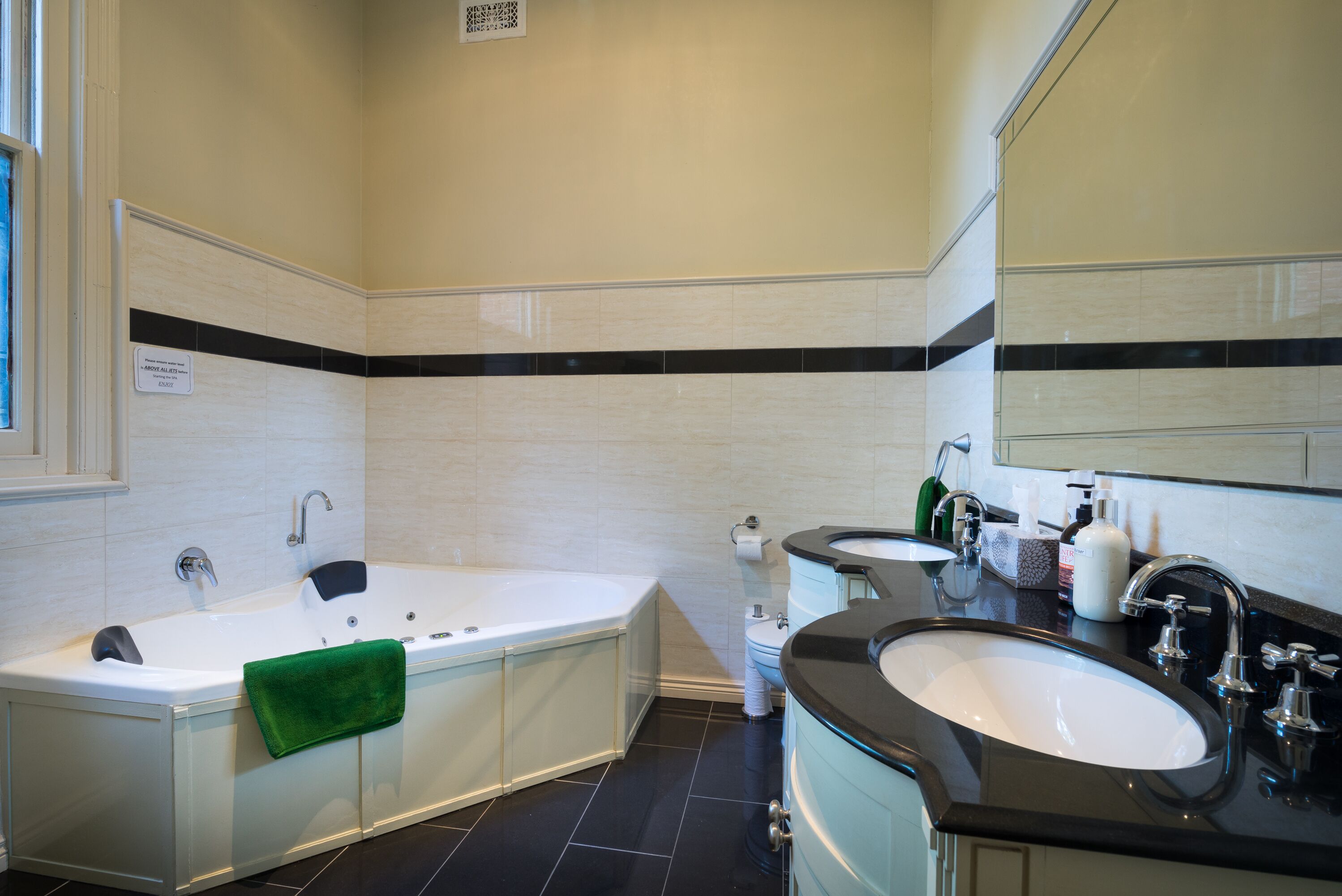 A modern bathroom with a bathtub, two sinks, and a large mirror.