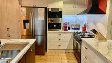 Una cocina moderna con electrodomésticos de acero inoxidable, armarios blancos y suelo de madera.
