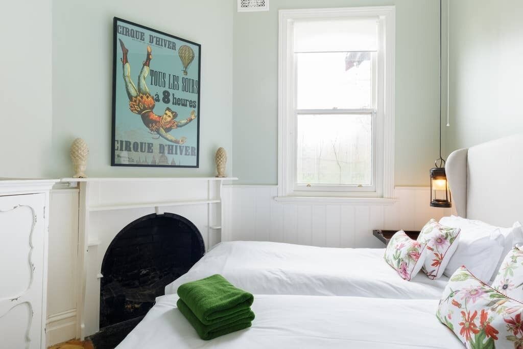 A bedroom with a bed, a fireplace, a window, and a wall poster.