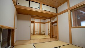 Una habitación japonesa tradicional con suelo de tatami, puertas correderas y techo de madera.