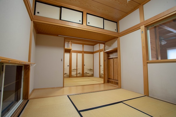 A traditional Japanese room with tatami flooring, sliding doors, and a wooden ceiling.