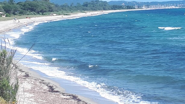A coastal beach with clear blue waters and a sandy shore.