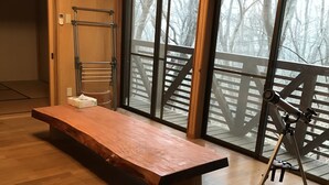 A spacious room with a wooden bench, a telescope, and large windows with a view of a wooden deck and trees. - Nasu Holiday (Nasu)
