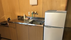 A compact kitchen with wooden cabinets, a stainless steel refrigerator, a sink, and a small countertop. - Nasu Holiday (Nasu)