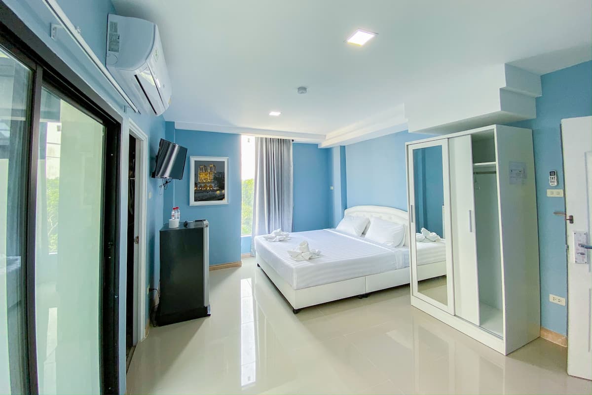 A modern hotel room with a bed, a wardrobe, a desk, and a television.