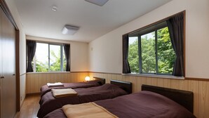 Ein Hotelzimmer mit zwei Betten, Holzwandverkleidung, großen Fenstern mit Vorhängen und einer Deckenleuchte.