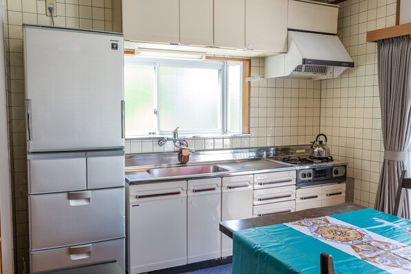 A compact kitchen with a refrigerator, stove, sink, and cabinets.