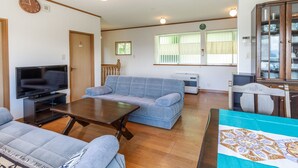 Ein Wohnzimmer mit einer Couch, einem Fernseher, einem Tisch und einem Schrank.