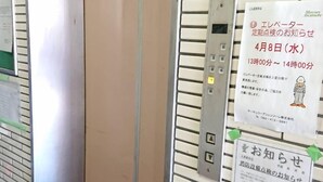 Ein Aufzug mit Bedienfeld und Informationsplakaten an der Wand.