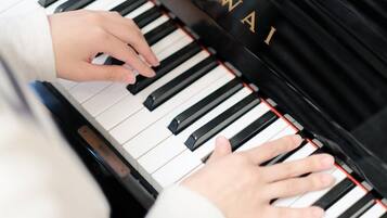 A close-up of hands playing a piano with the brand name "AWAI" visible on the side.