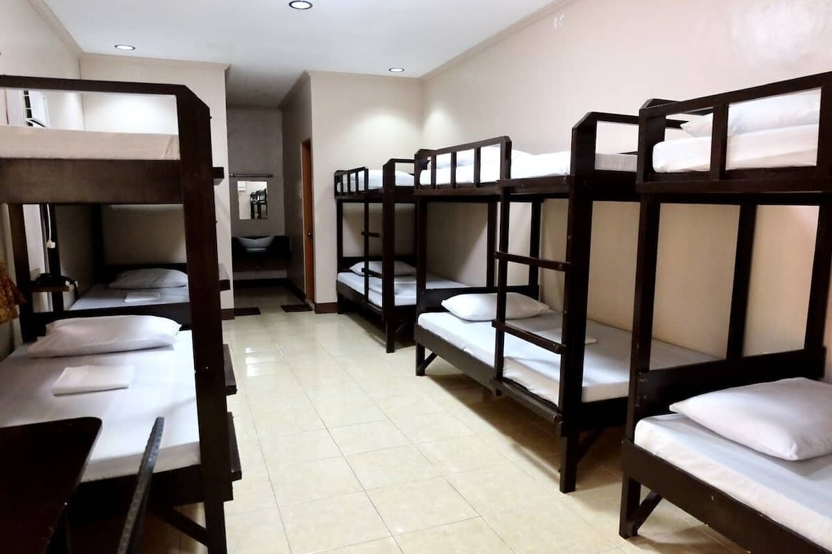 A dormitory room with bunk beds, a desk, and a chair.