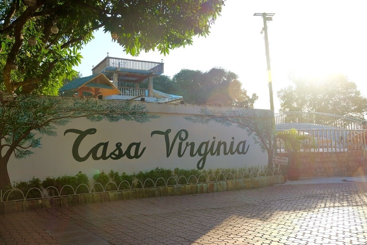 A sign for "Tasa Virginia" with a building in the background.