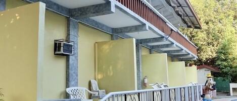 Un edificio con fachada amarilla, un porche cubierto con escalones y una barandilla de metal.