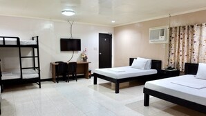 A dormitory room with bunk beds, a desk, a chair, a TV, and a door. - Casa Virginia Resort (San Narciso)