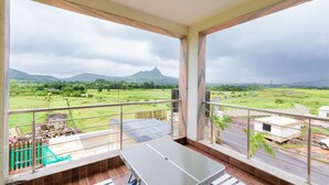 Un balcon offrant une vue sur un paysage verdoyant et des montagnes lointaines.