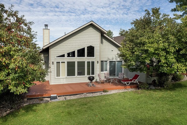 A house with a sloped roof, large windows, and a patio with outdoor furniture.