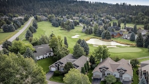 Vista aérea de una zona residencial con casas, un campo de golf y un estanque.