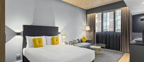 Een moderne hotelkamer met een groot bed, een sofa, een tafeltje en een televisie.