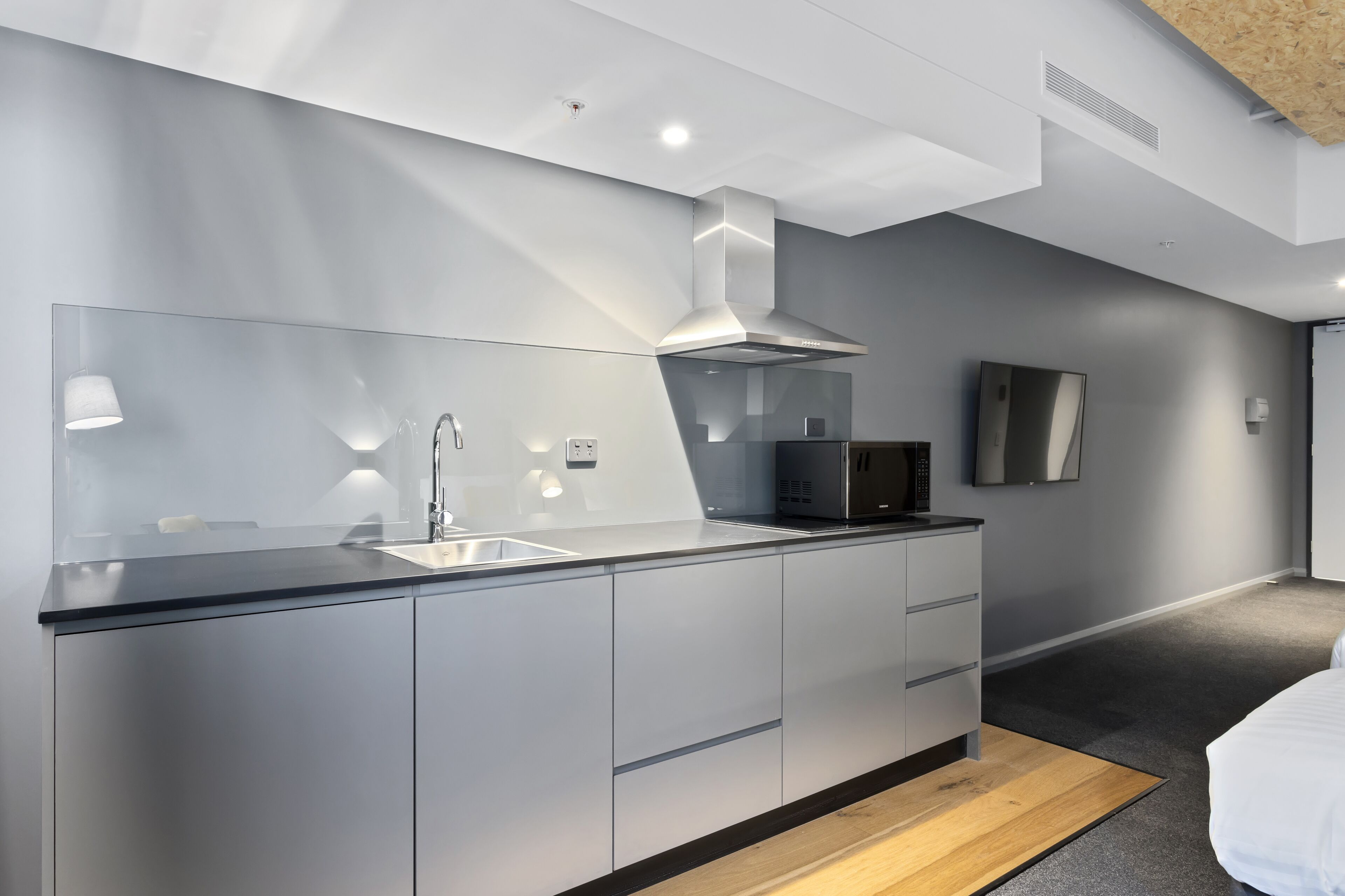 A modern kitchen with a sleek design, including a stainless steel range hood, a built-in sink, and a microwave.
