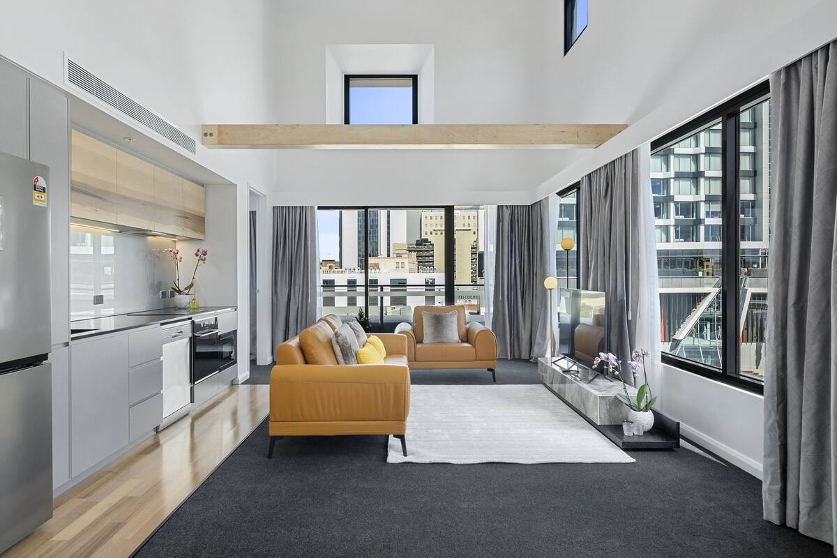 A modern apartment with a kitchen, living area, and large windows offering city views.