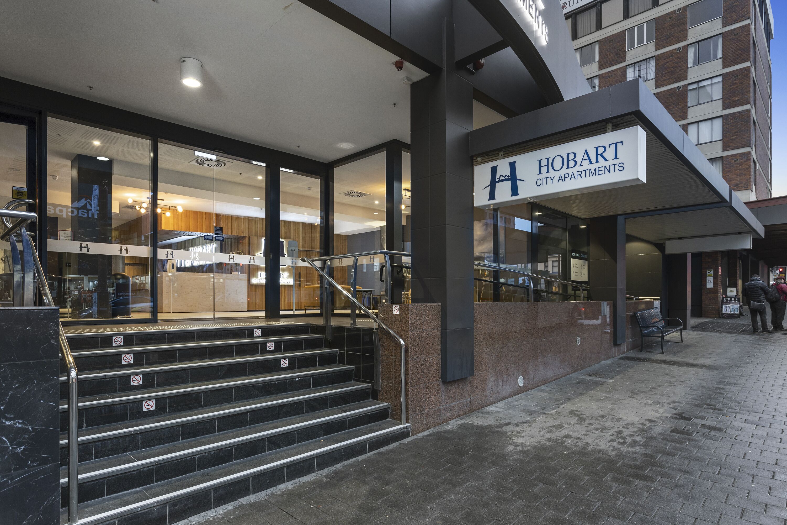 A modern building entrance with a sign for Hobart City Apartments.