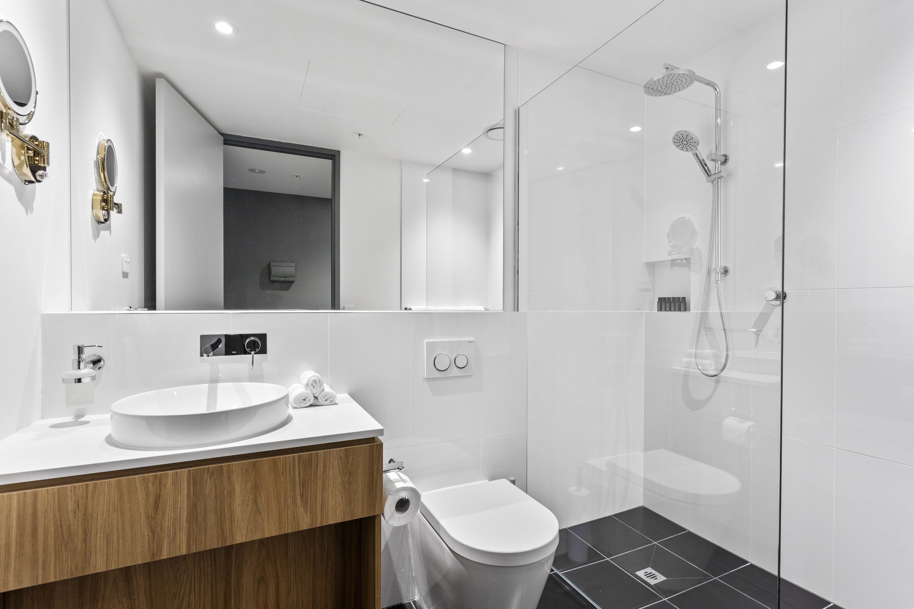 Een moderne badkamer met een ronde wastafel, een toilet en een douchecabine met glazen wanden.