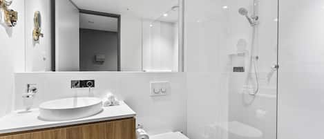 A modern bathroom with a round sink, a toilet, and a glass-enclosed shower area.