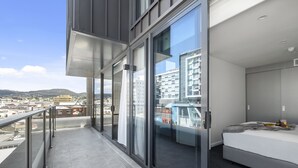 Habitación de hotel moderna con balcón, ventanas amplias y vista a la ciudad.
