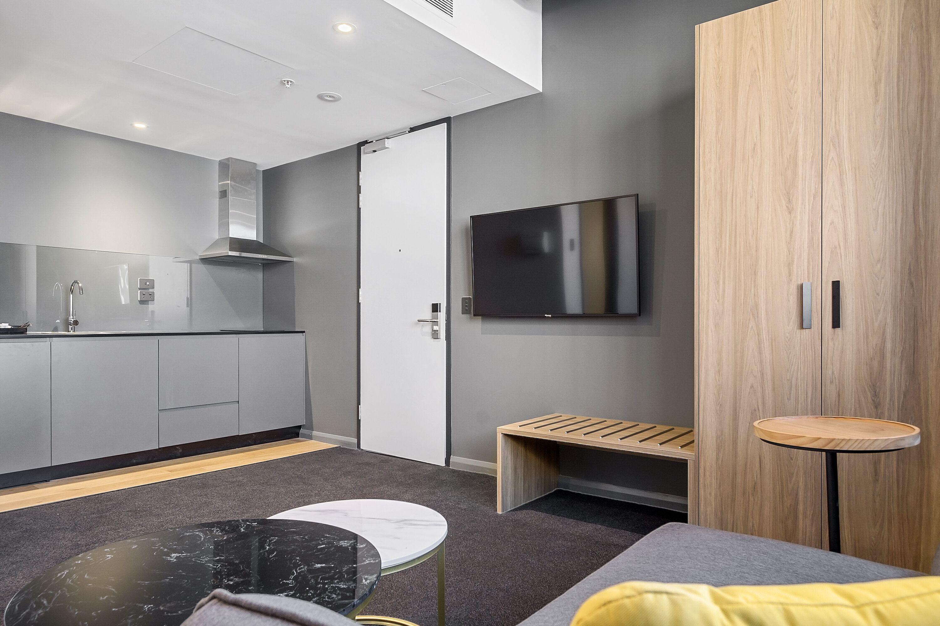 A modern kitchen with grey cabinets, a stainless steel range hood, and a built-in oven.
