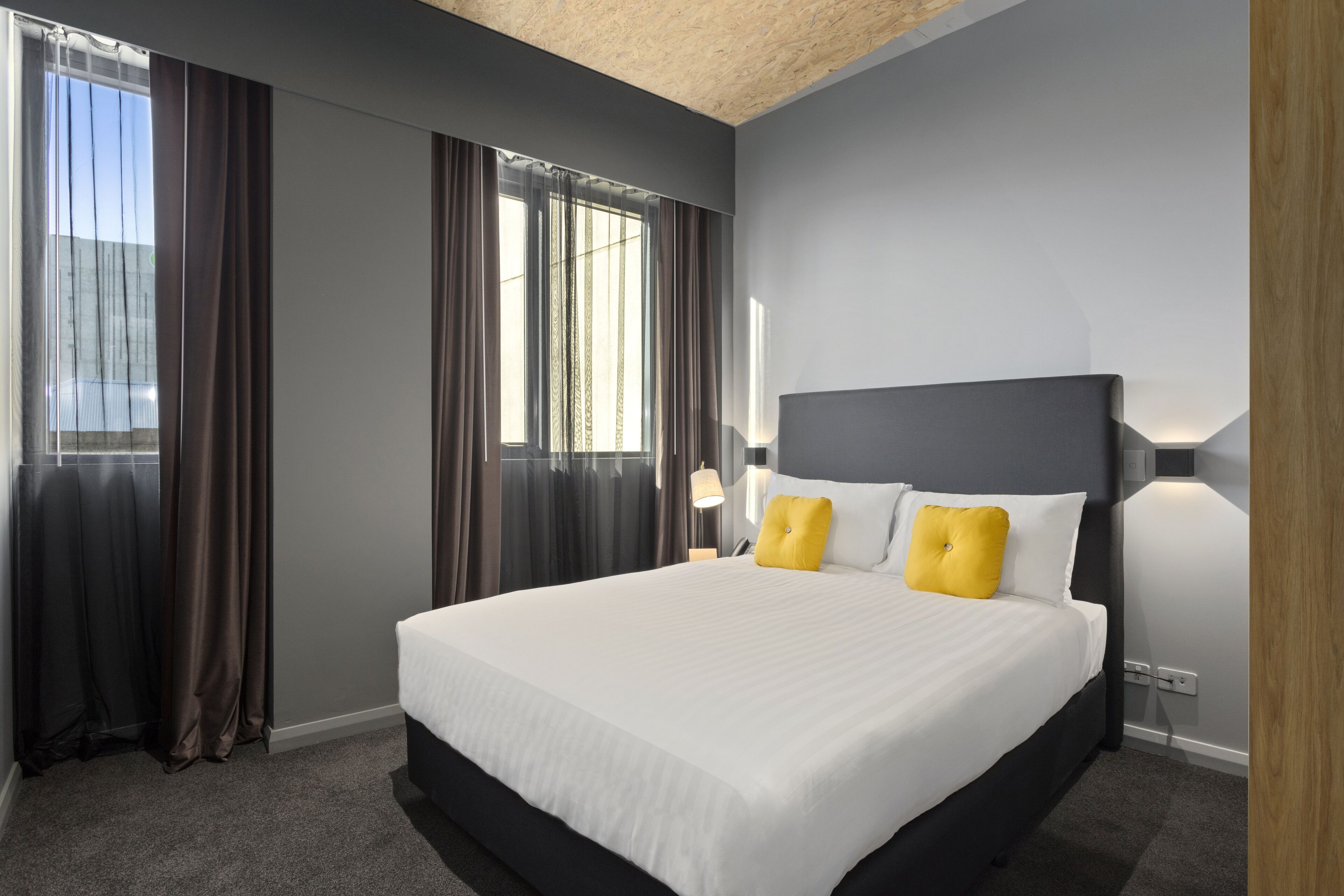 Ein modernes Hotelzimmer mit einem großen Bett, dunklen Wänden und Blick auf die Stadt.