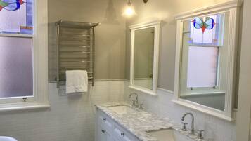 Un baño con dos lavamanos, un espejo, un perchero para toallas y una ventana con vitrales.