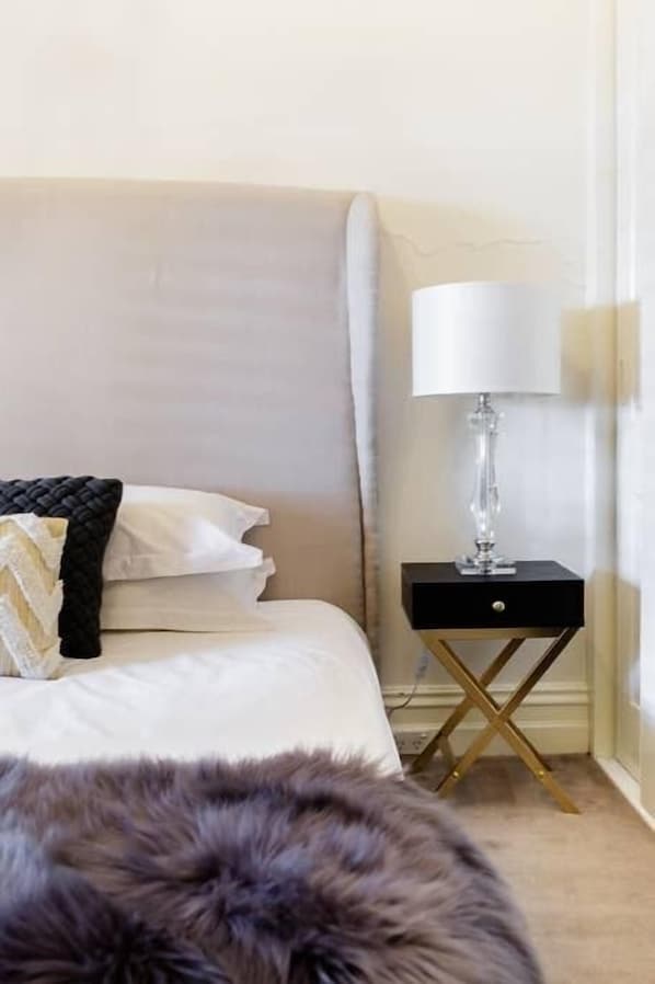 Une chambre à coucher avec un lit, une table de chevet avec une lampe et un tapis moelleux.