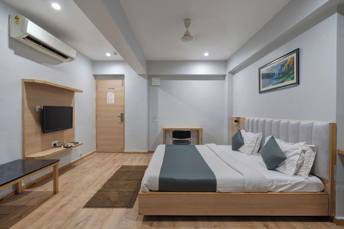 Une chambre moderne avec un lit en bois, un téléviseur à écran plat, un bureau et un tableau accroché au mur.