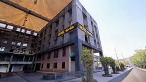 Un hotel de varios pisos con un llamativo letrero amarillo que dice "HOTEL Berlin" y un amplio alero que proporciona sombra.