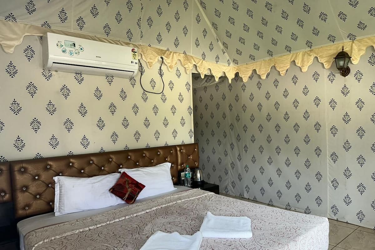 A neatly made bed with a patterned bedspread, a brown headboard, and a decorative wall hanging.