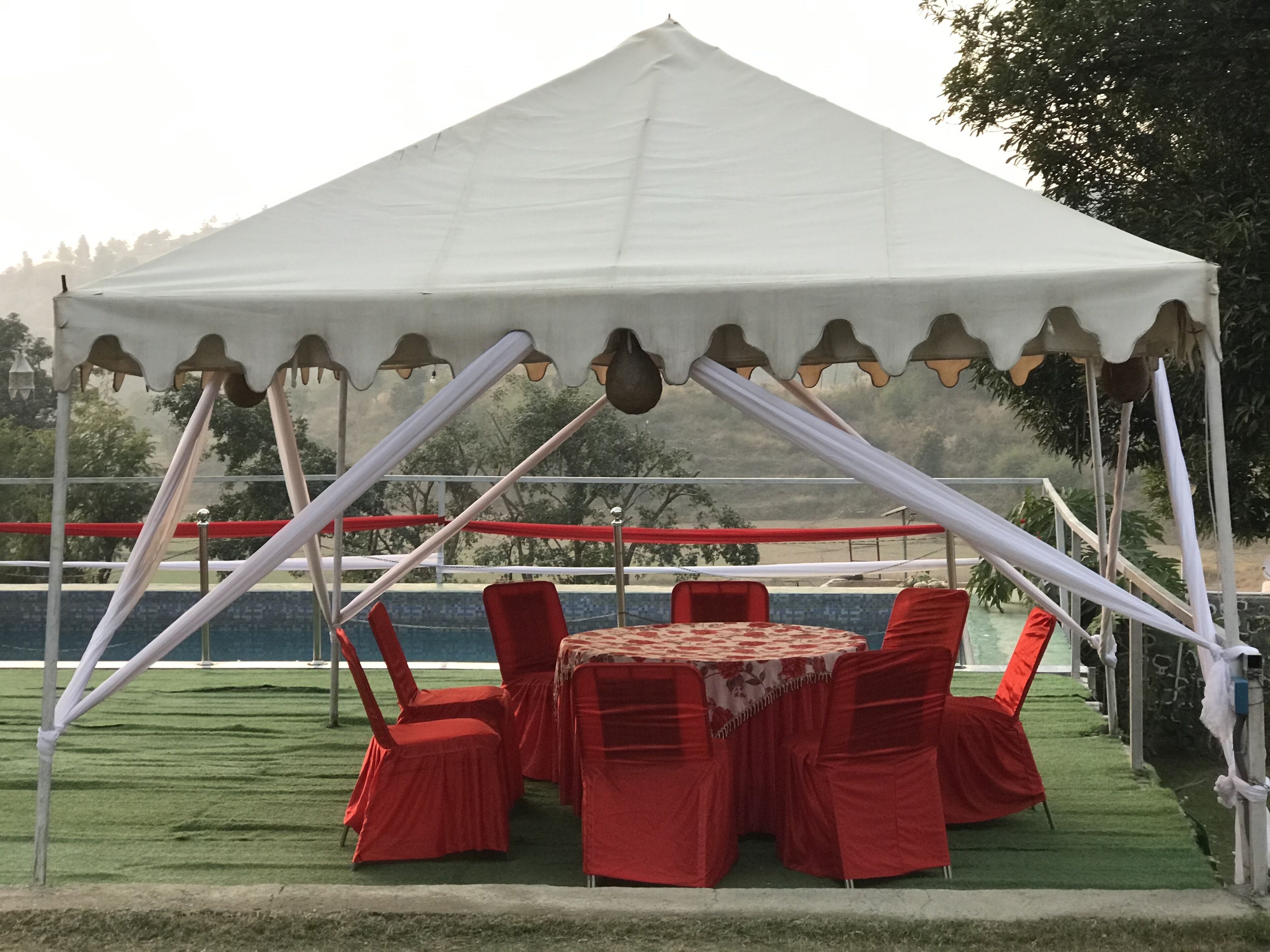 A tent with a table and chairs set up on a grassy area with a view of a body of water.