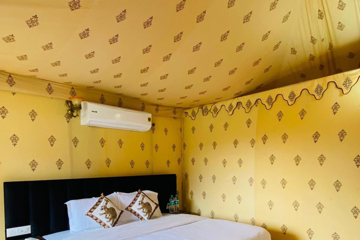 A bedroom with a bed, a nightstand, and a wall-mounted air conditioner.
