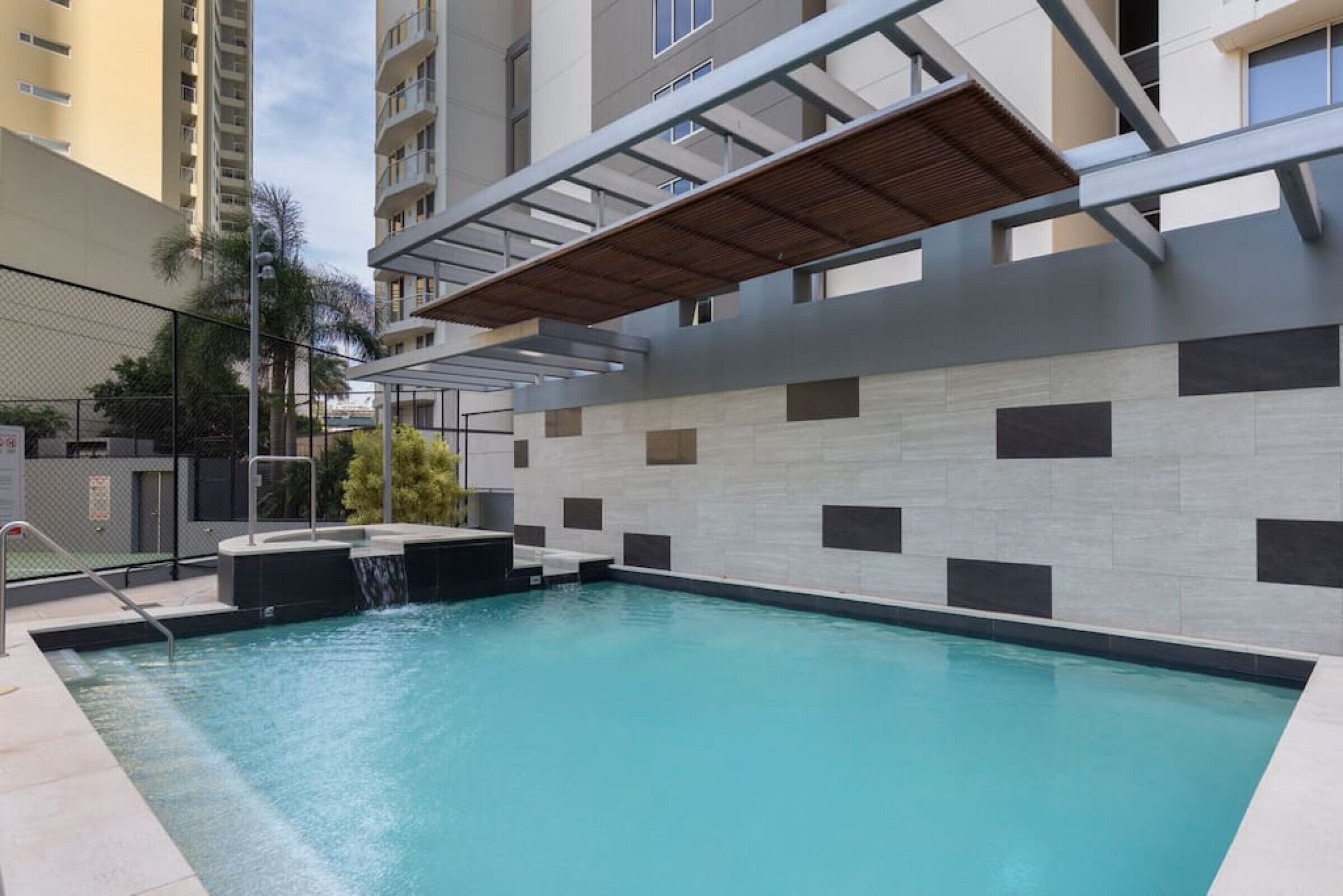 A swimming pool with a wooden deck and a waterfall feature.